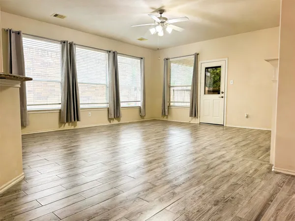 an empty room with wooden floor and windows