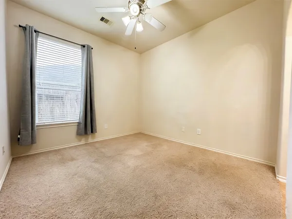 an empty room with windows and fan