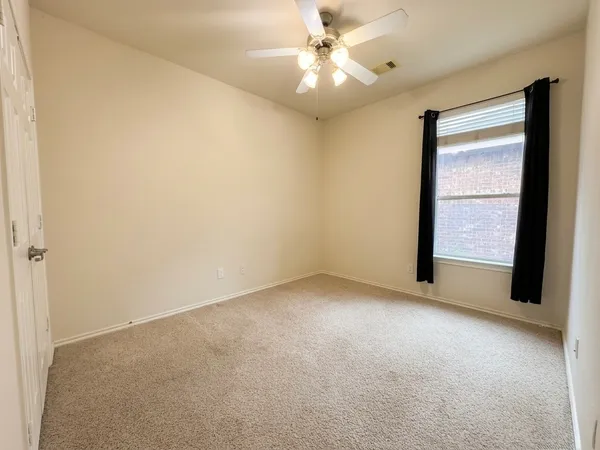 an empty room with a window and a fan