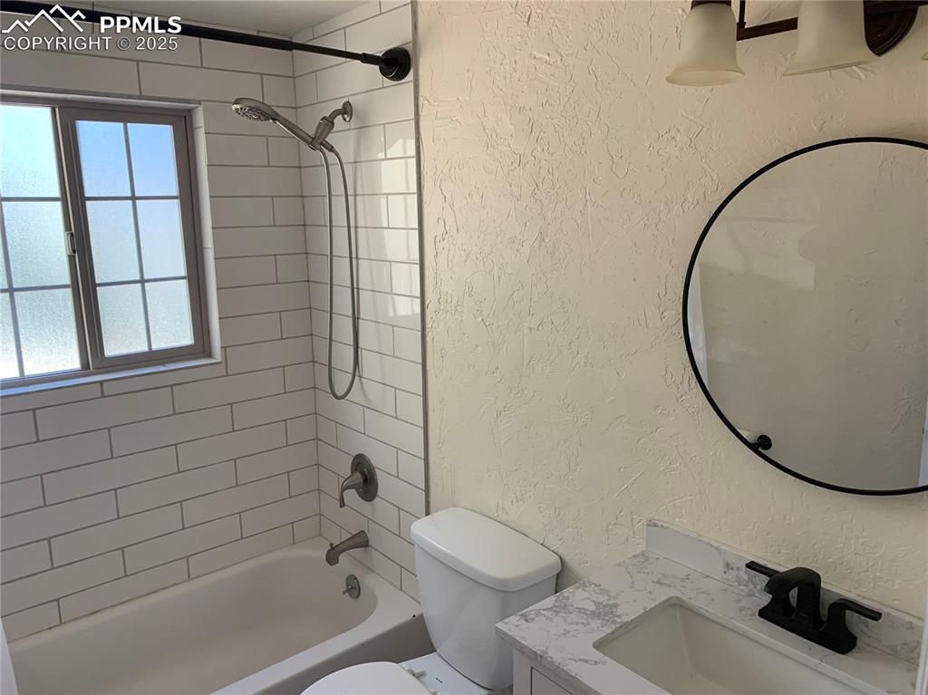 1057 Peterson Road Colorado Springs, CO 80915 - Photo 18 of 32 Full bath featuring a textured wall, bathtub / shower combination, and vanity