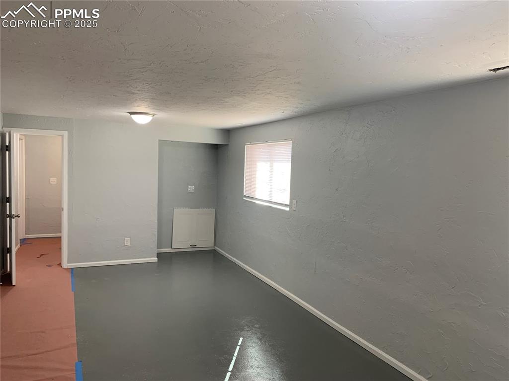 1057 Peterson Road Colorado Springs, CO 80915 - Photo 22 of 32 Spare room with a textured wall, concrete floors, and a textured ceiling