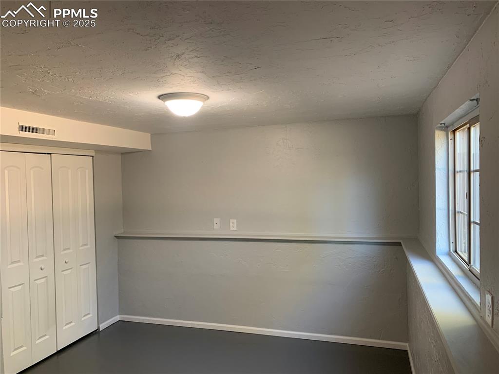 1057 Peterson Road Colorado Springs, CO 80915 - Photo 26 of 32 Unfurnished bedroom with a textured ceiling and a closet