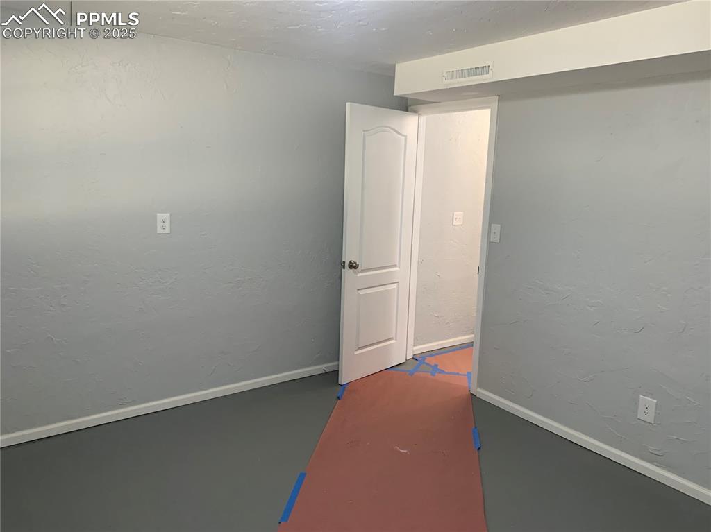 1057 Peterson Road Colorado Springs, CO 80915 - Photo 29 of 32 Empty room with a textured wall, a textured ceiling, and concrete floors