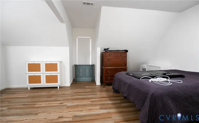 a view of an empty room with wooden floor and a fan