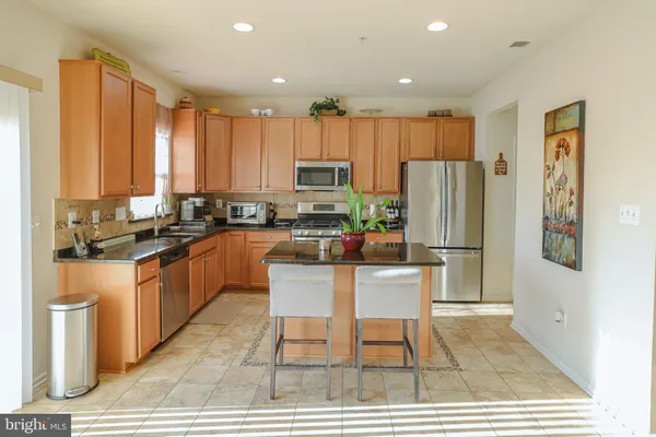 a kitchen with stainless steel appliances granite countertop a refrigerator a stove a sink and white cabinets with wooden floor