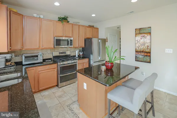 a kitchen with stainless steel appliances kitchen island granite countertop a stove refrigerator sink and cabinets