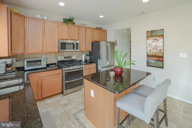 a kitchen with stainless steel appliances kitchen island granite countertop a stove refrigerator sink and cabinets