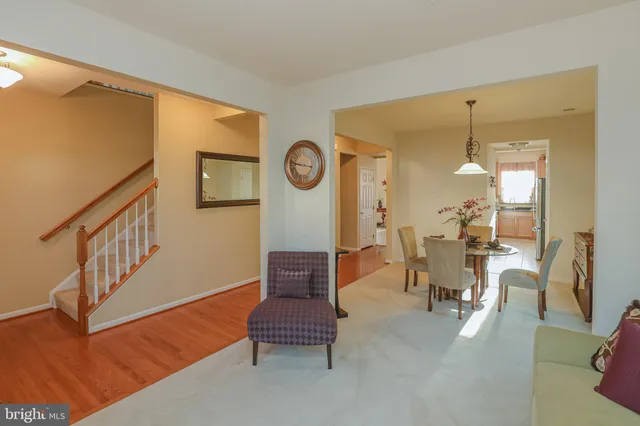 a living room with couches and a dining table with wooden floor