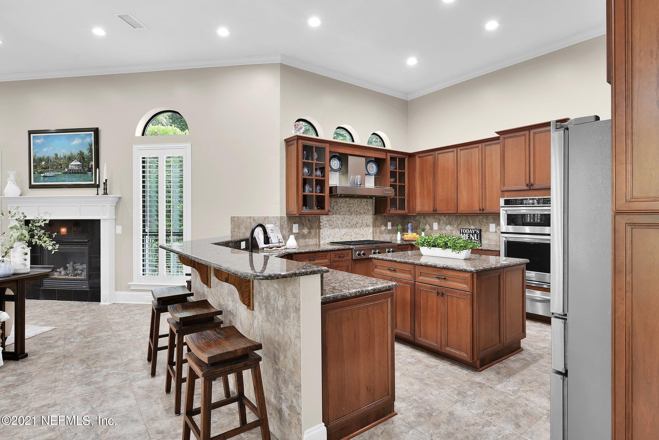 142 Marshall Creek Drive St. Augustine, FL 32095 - Photo 33 of 176 a kitchen with stainless steel appliances granite countertop a refrigerator a sink dishwasher a stove and a dining table with wooden floor