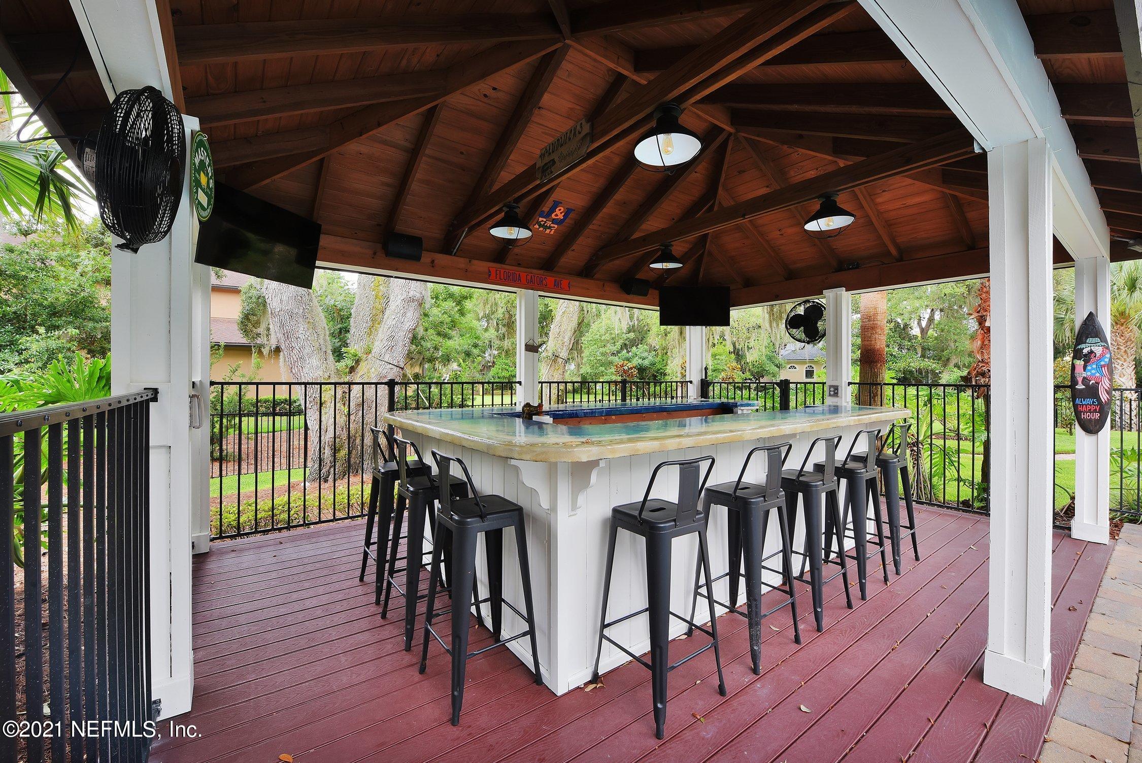 142 Marshall Creek Drive St. Augustine, FL 32095 - Photo 97 of 176 a view of a patio with table and chairs under an umbrella with wooden floor