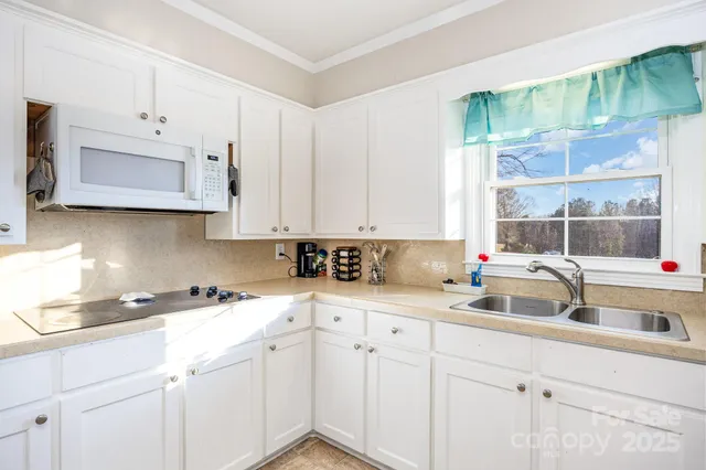 a kitchen with stainless steel appliances a sink a stove and white cabinets