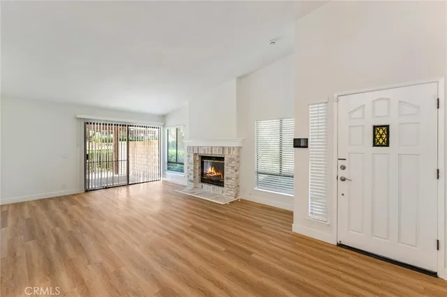 a view of an empty room with wooden floor fireplace and a window