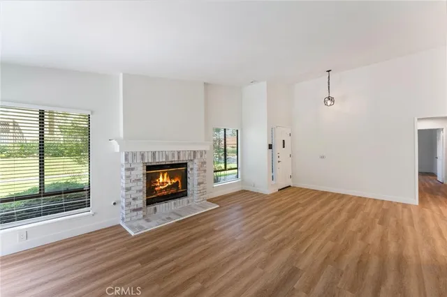 a view of an empty room with wooden floor fireplace and a window