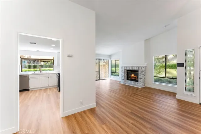 an empty room with wooden floor fireplace and windows