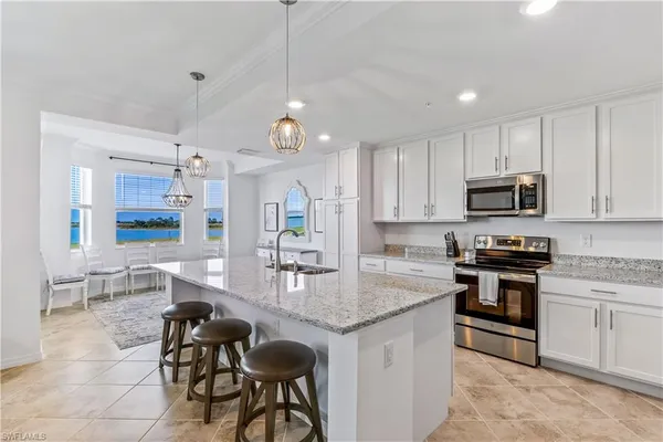 a kitchen with stainless steel appliances granite countertop a stove top oven a sink a dining table and chairs