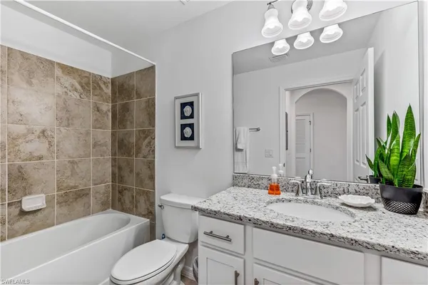 a bathroom with a granite countertop sink a toilet and bathtub