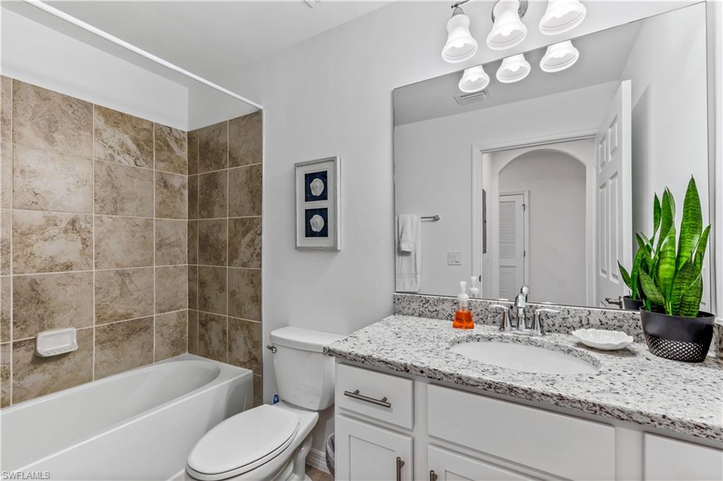 43030 Greenway Boulevard, Unit 423 Babcock Ranch, FL 33982 - Photo 10 of 11 a bathroom with a granite countertop sink a toilet and bathtub