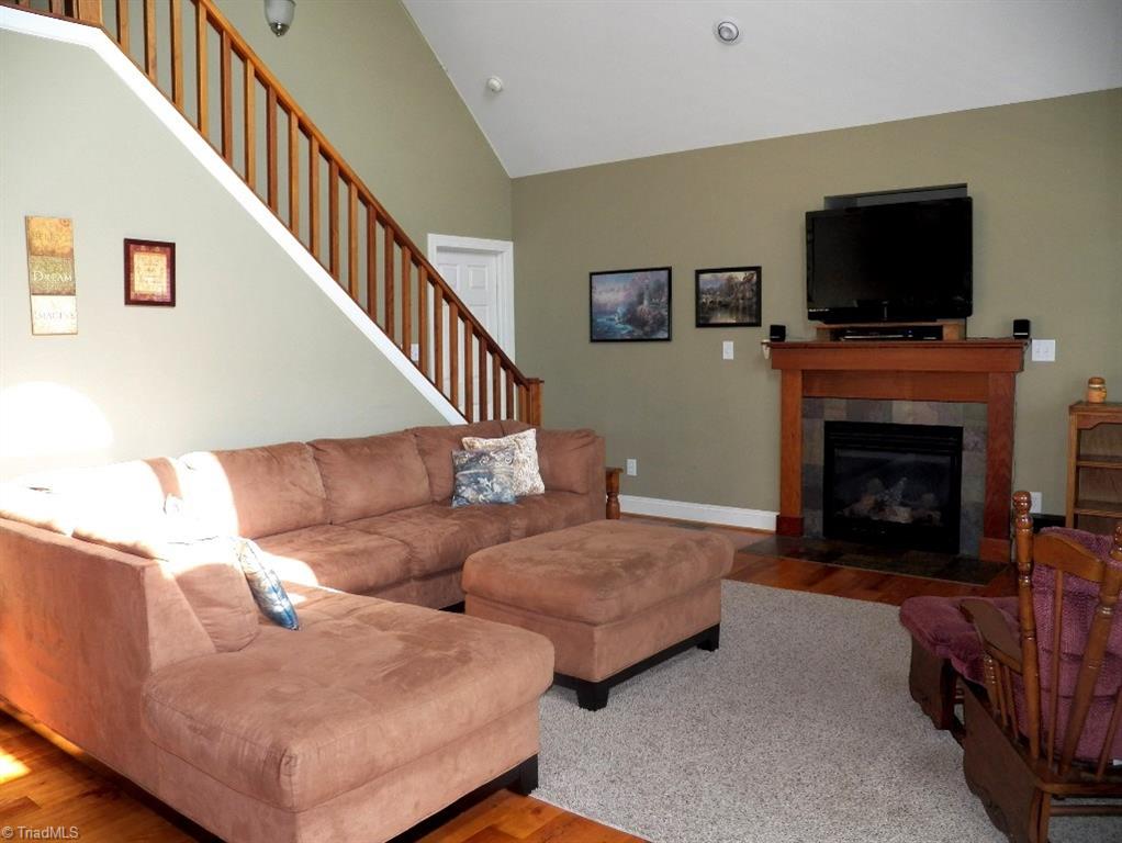 859 Riverview Rd Extension Lexington, NC 27292 - Photo 10 of 26 View of living area from the front door. Gas fireplace with area for flat screen TV above. Cathedral ceiling with lights and large ceiling fan. Pine wood floors. Stairs to upstairs loft area.