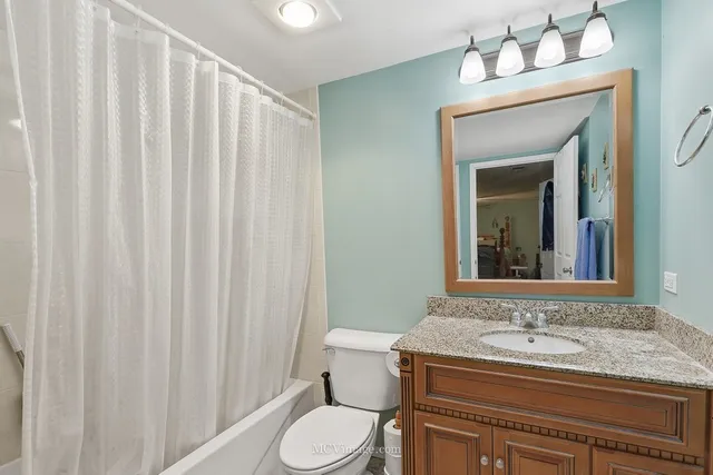 a bathroom with a granite countertop sink vanity mirror and toilet