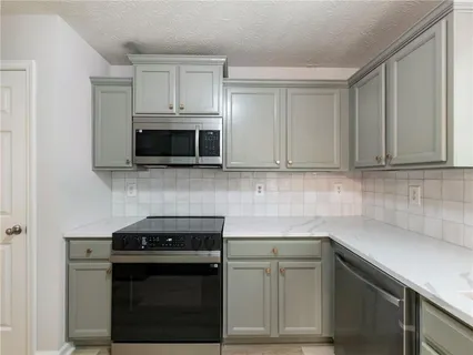 a kitchen with stainless steel appliances granite countertop white cabinets and a stove top oven