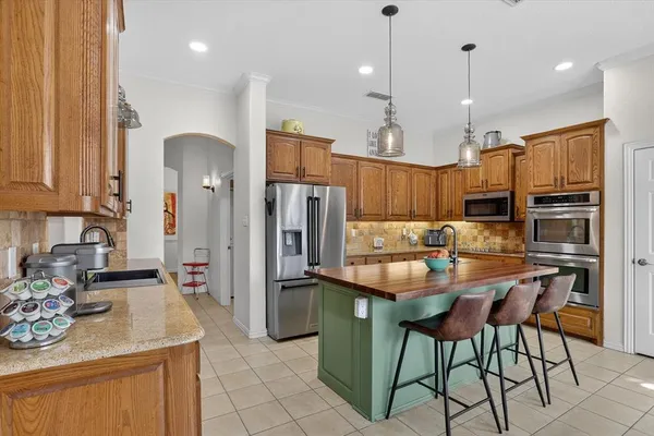a kitchen with stainless steel appliances kitchen island granite countertop a refrigerator a stove a sink dishwasher and a dining table with wooden floor