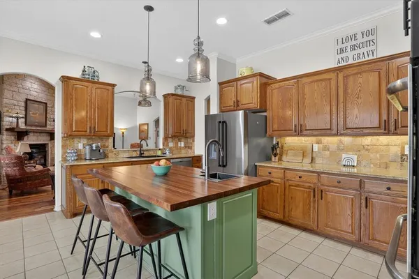 a kitchen with stainless steel appliances granite countertop a table chairs refrigerator and sink