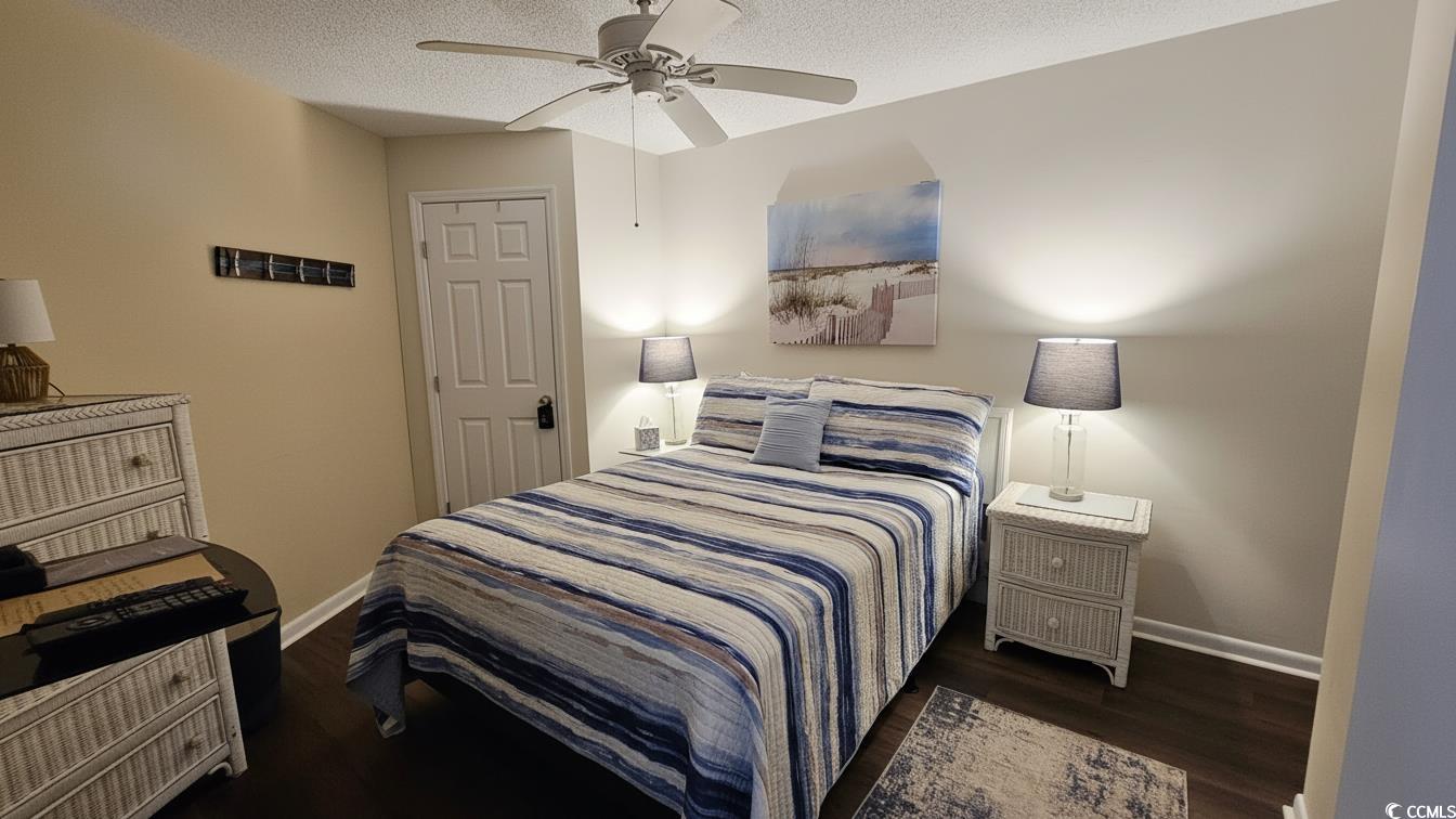 1210 North Waccamaw Drive, Unit 512 Murrells Inlet, SC 29576 - Photo 12 of 20 Bedroom featuring dark wood-style floors, a ceiling fan, and a textured ceiling