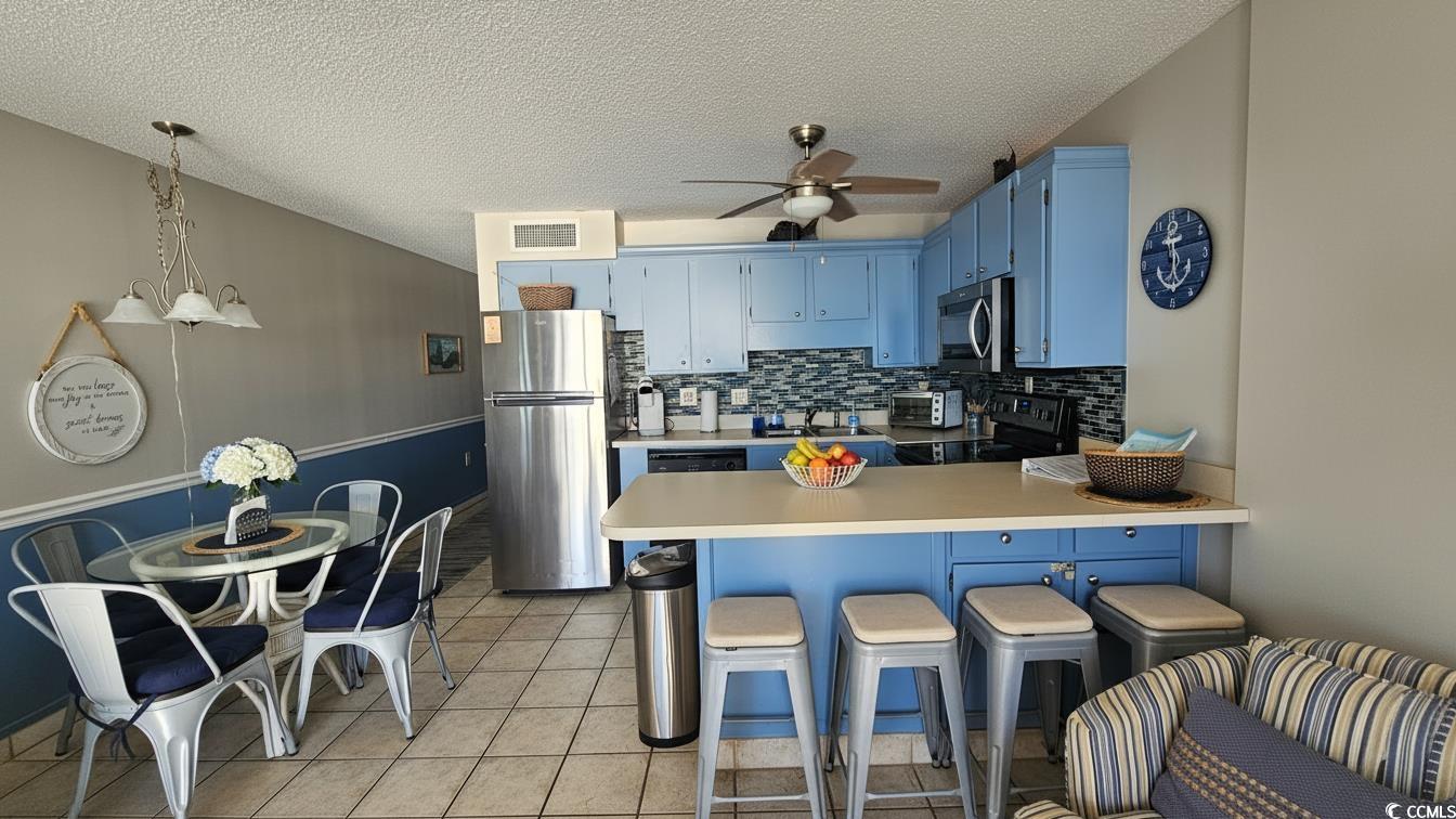 1210 North Waccamaw Drive, Unit 512 Murrells Inlet, SC 29576 - Photo 8 of 20 Kitchen featuring blue cabinetry, a kitchen bar, a peninsula, light countertops, and hanging light fixtures