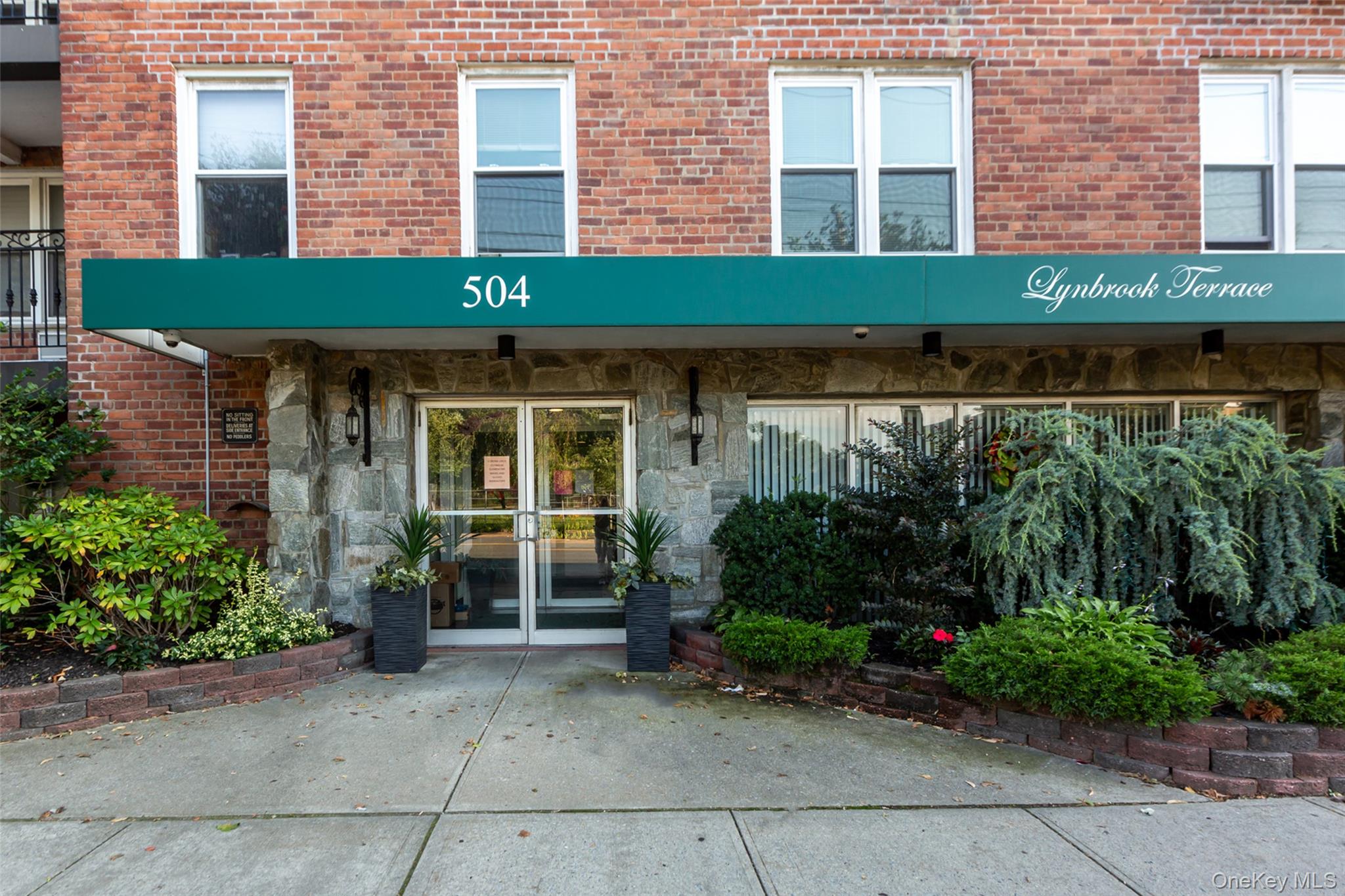 504 Merrick Road, Unit 2K Lynbrook, NY 11563 - Photo 2 of 20 a front view of a building with garden
