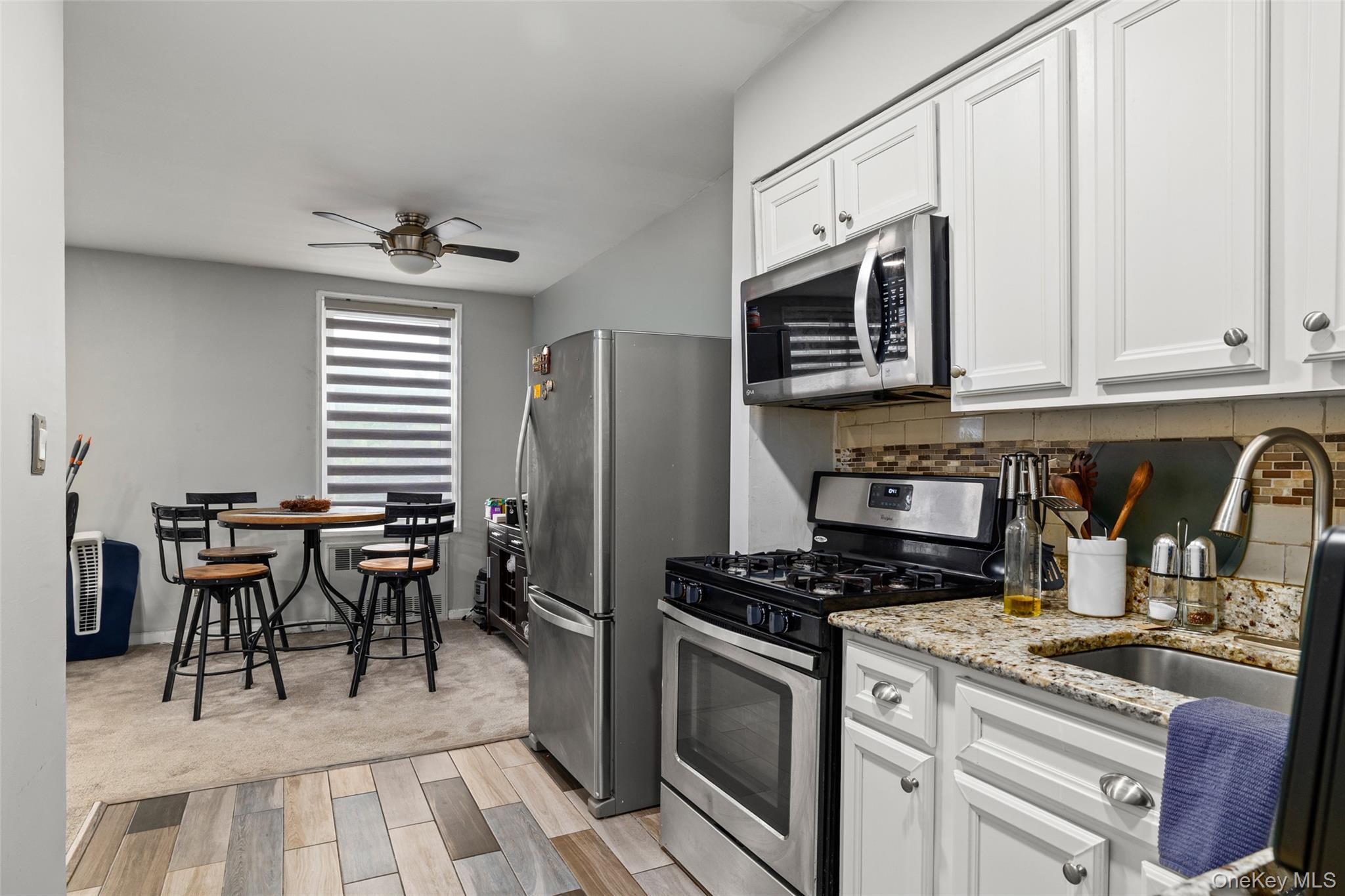 504 Merrick Road, Unit 2K Lynbrook, NY 11563 - Photo 8 of 20 a kitchen with stainless steel appliances granite countertop a stove top oven a refrigerator a sink and white cabinets