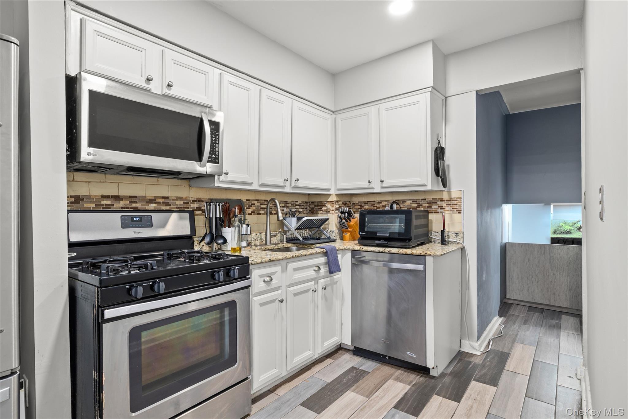 504 Merrick Road, Unit 2K Lynbrook, NY 11563 - Photo 9 of 20 a kitchen with stainless steel appliances a stove a microwave a sink and cabinets