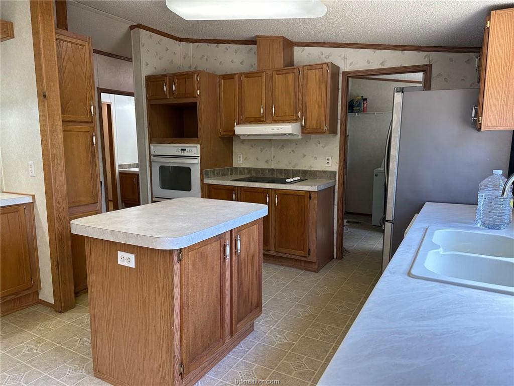 3180 Henderson Road Millican, TX 77868 - Photo 4 of 10 a kitchen with stainless steel appliances a stove refrigerator sink and microwave