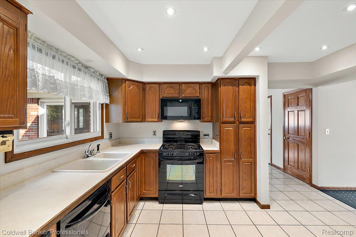 78 Carter Avenue Troy, MI 48098 - Photo 14 of 52 Kitchen with black appliances, light countertops, brown cabinetry, light tile patterned floors, and recessed lighting
