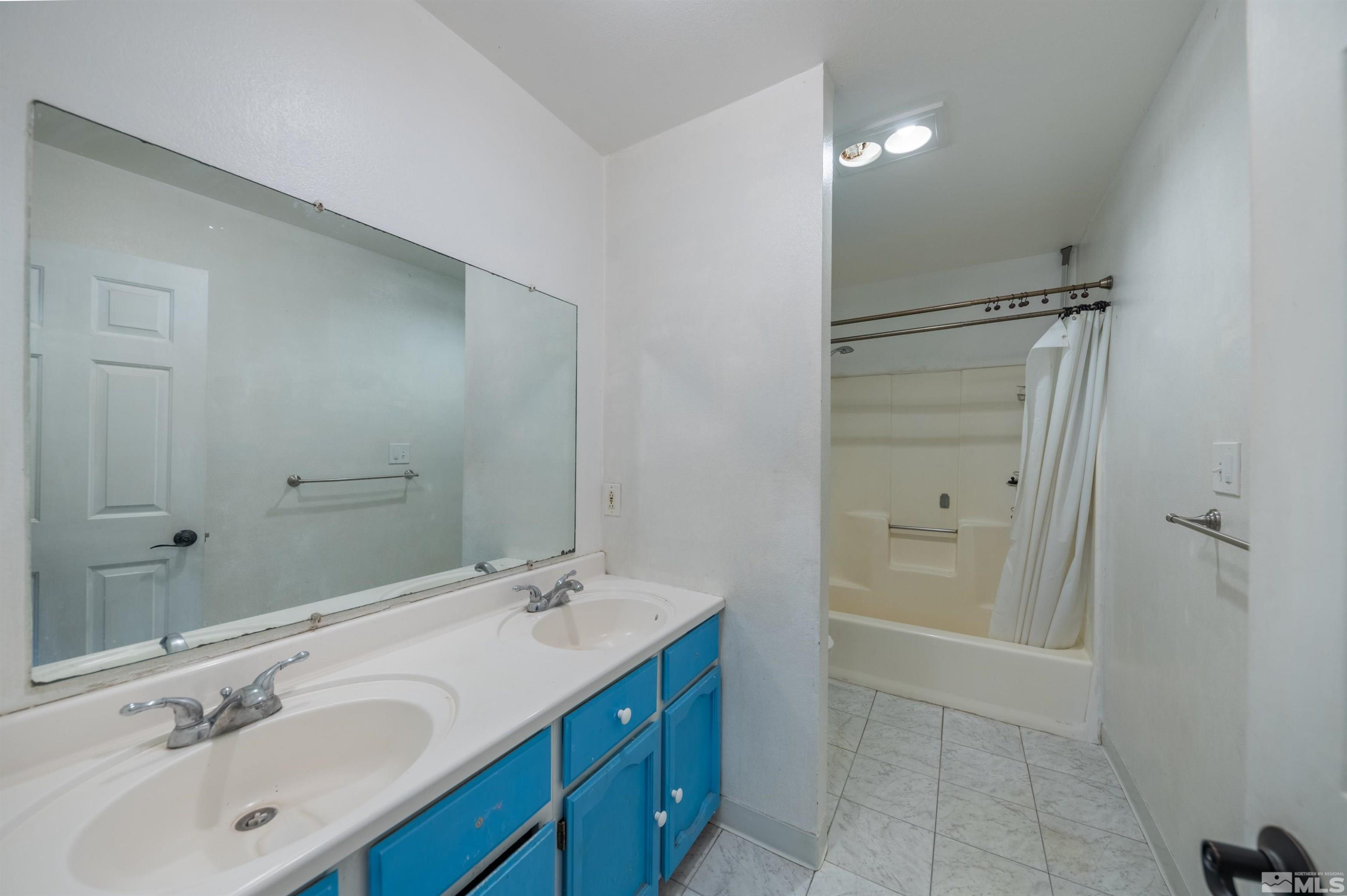 10880 Deodar Way Reno, NV 89506 - Photo 15 of 38 a bathroom with a tub sink double vanity and a mirror