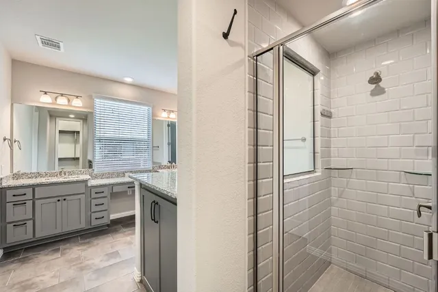a bathroom with a double vanity sink a toilet and shower