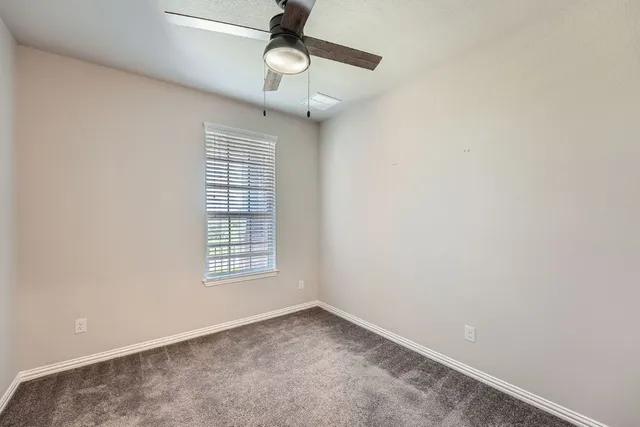 en empty room with windows and ceiling fan