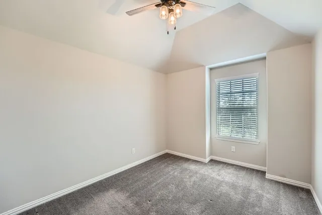 an empty room with a chandelier fan and windows