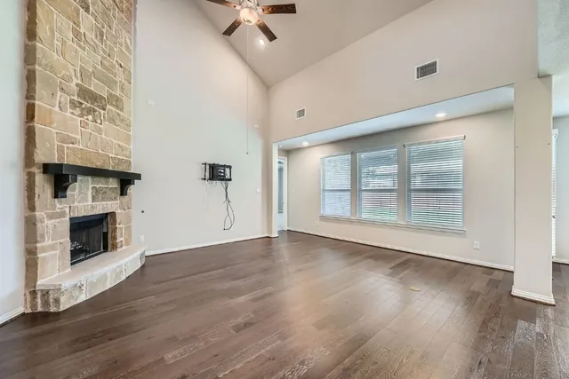 a view of an empty room with wooden floor fireplace and a window