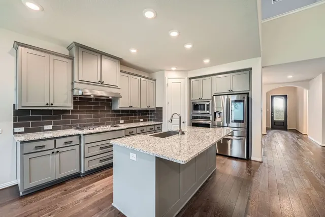 a kitchen with stainless steel appliances granite countertop a lot of counter space and wooden floors