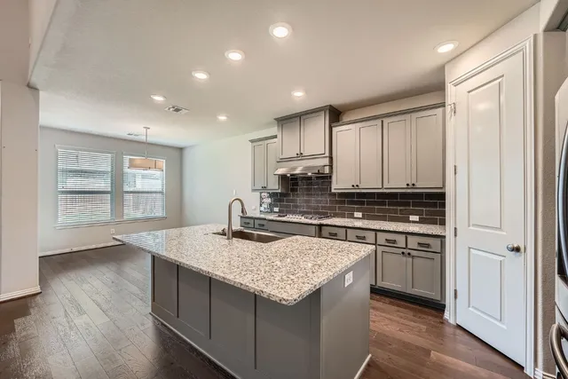 a kitchen with kitchen island granite countertop a stove and a sink