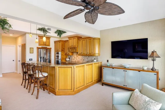 a kitchen with stainless steel appliances kitchen island granite countertop a table chairs and a refrigerator
