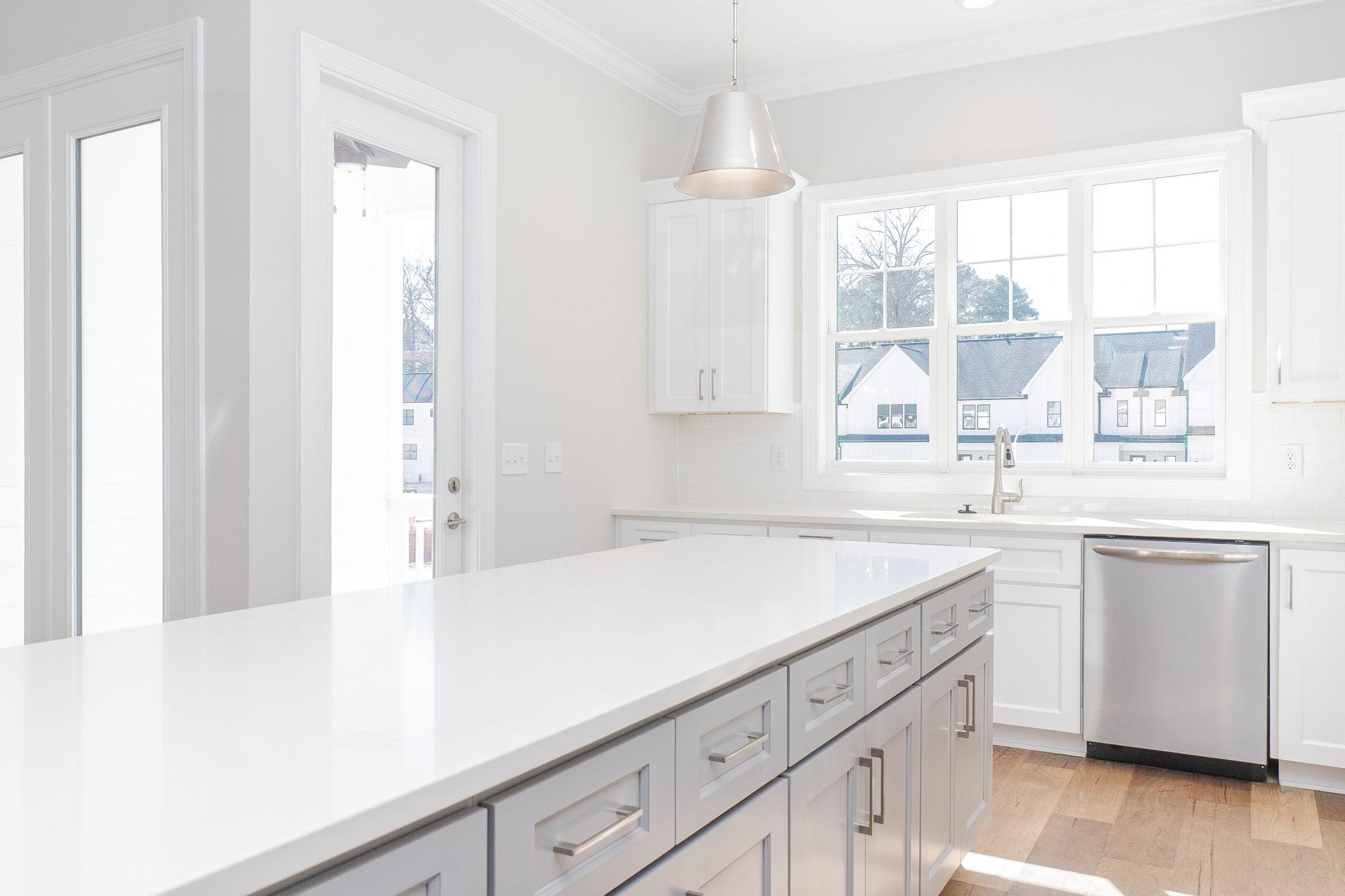 4916 Trek Lane Raleigh, NC 27606 - Photo 15 of 28 a kitchen with a sink dishwasher and white cabinets with wooden floor