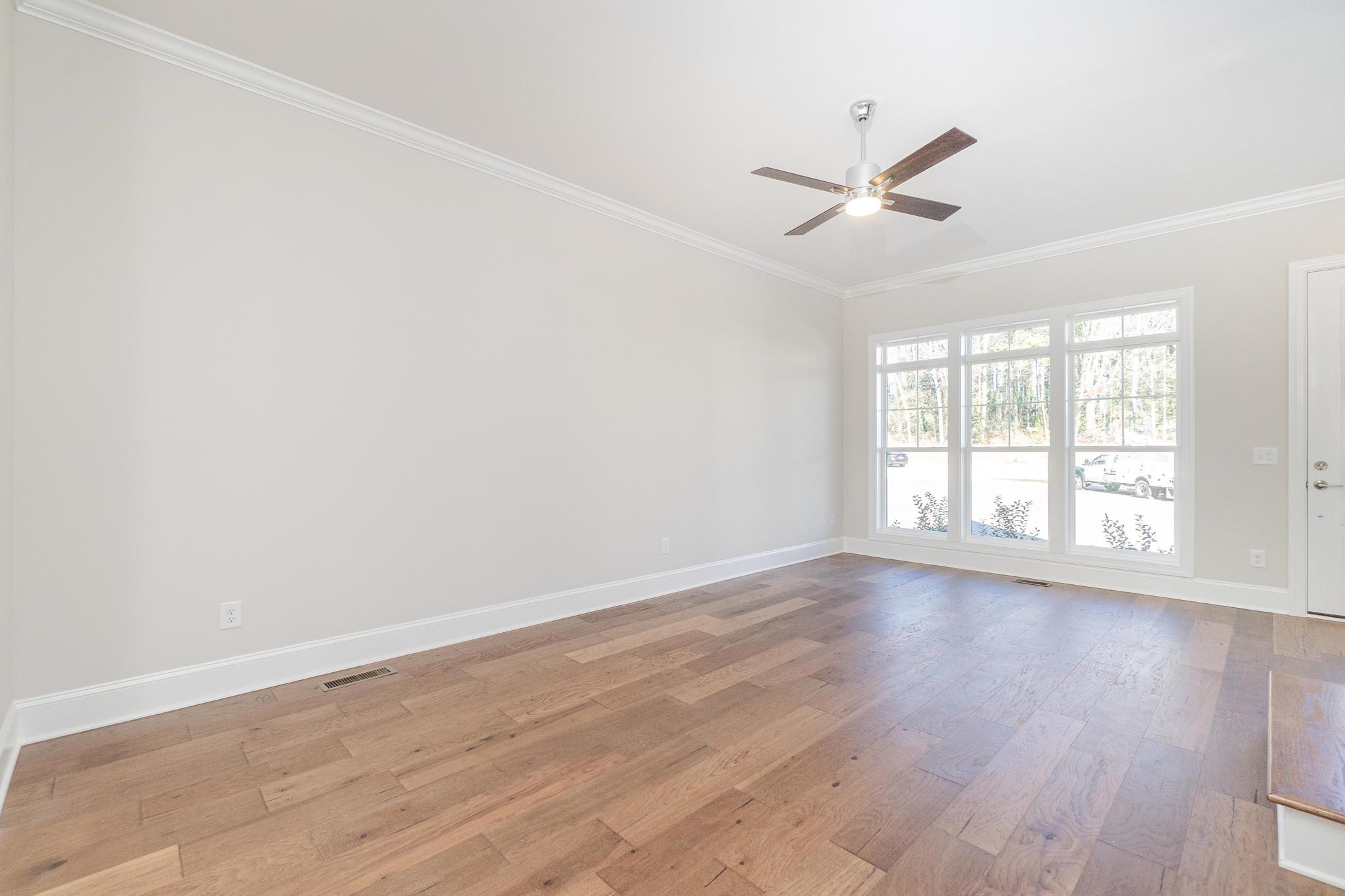 4916 Trek Lane Raleigh, NC 27606 - Photo 6 of 28 an empty room with wooden floor fan and windows