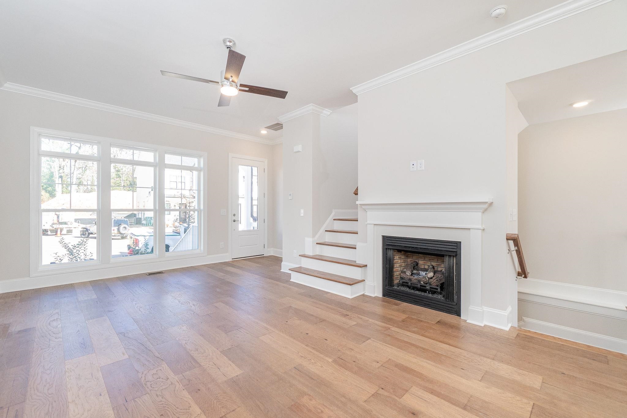 4916 Trek Lane Raleigh, NC 27606 - Photo 7 of 28 an empty room with wooden floor fireplace and windows