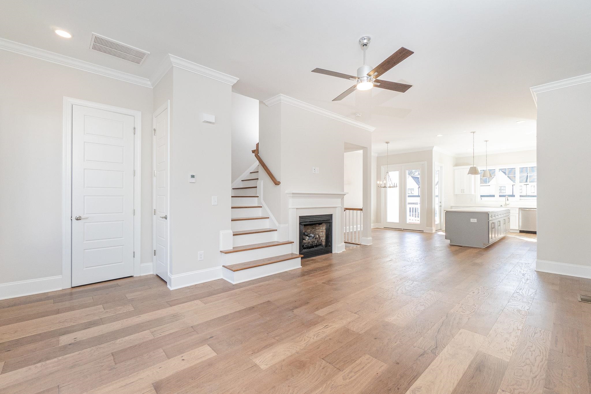 4916 Trek Lane Raleigh, NC 27606 - Photo 9 of 28 a view of a livingroom with wooden floor and a kitchen space with a ceiling fan