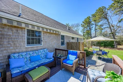 a view of a patio with couches table and chairs under an umbrella with a barbeque