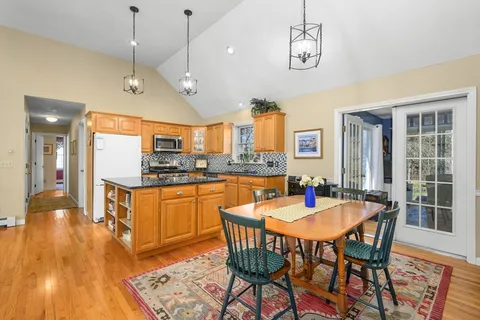 a dining room with stainless steel appliances granite countertop a sink a counter space a dining table and chairs