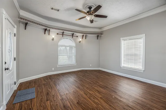 a view of empty room with wooden floor and fan