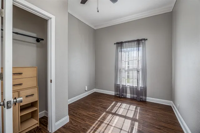 a view of an empty room with a window and wooden floor