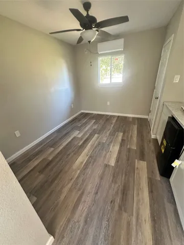 a view of empty room with wooden floor and fan